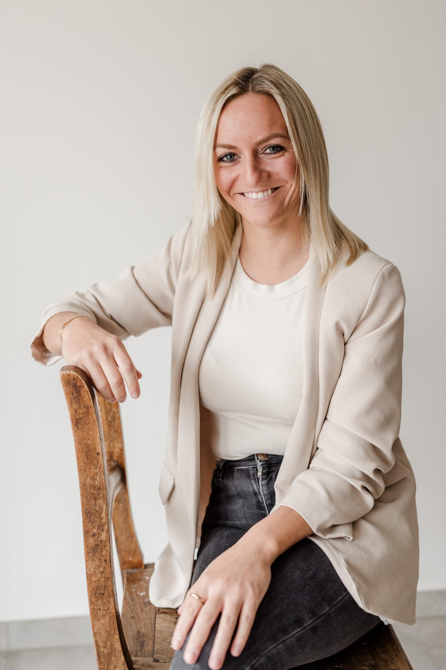 Eine lächelnde Frau sitzt auf einem Stuhl.